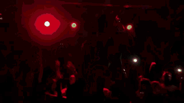 a man without a shirt is dancing in front of a crowd in a dark room .