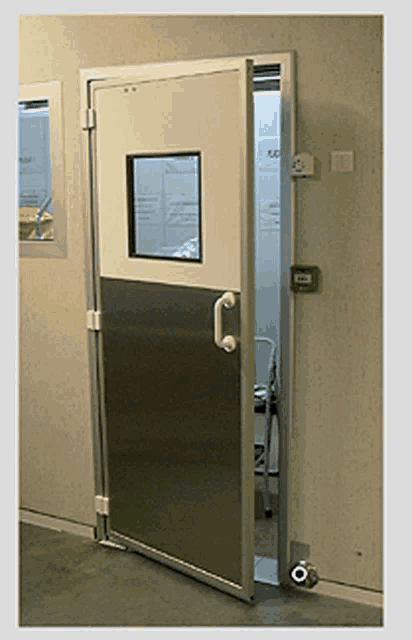 a stainless steel door with a small window and a green fire alarm button