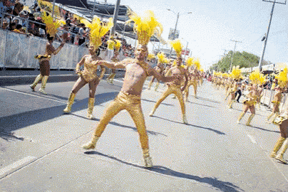 a group of people are dancing in a parade wearing gold outfits and yellow feathers