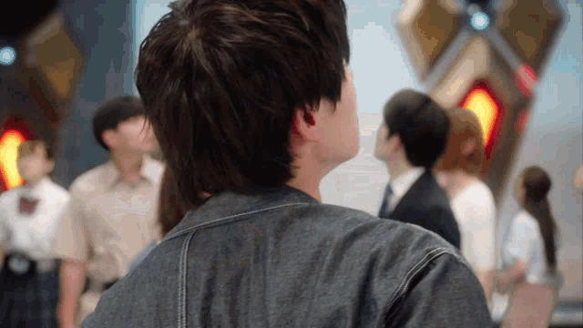 a man in a denim jacket is looking up at something