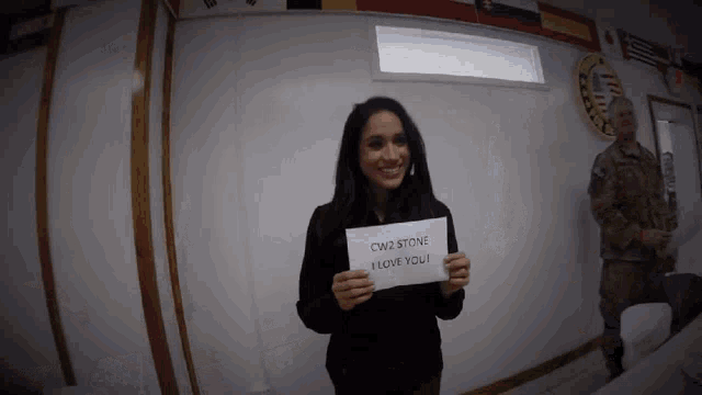a woman holding up a sign that says cw2 stone i love you