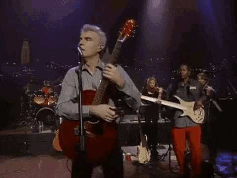 a man playing a guitar and singing into a microphone