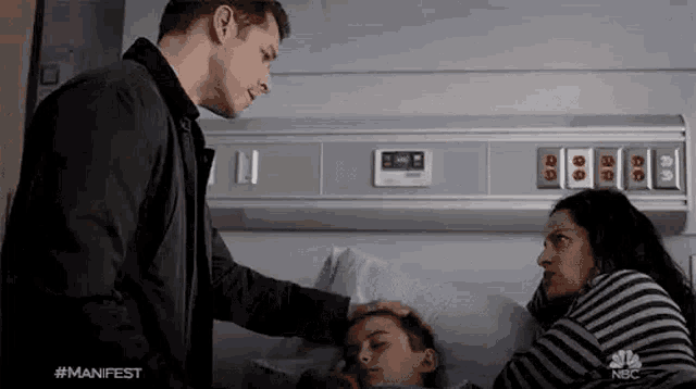 a man is putting his hand on a child 's head in a hospital bed .