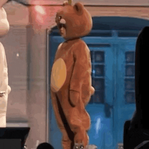 a child in a teddy bear costume is standing in front of a crowd .