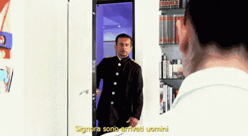 a man in a black suit is standing in front of a door with the words signora sono arrivati uomini above him