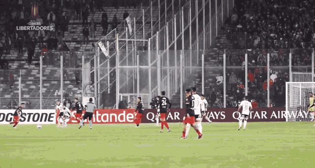 soccer players on a field with an ad for qatar airways behind them