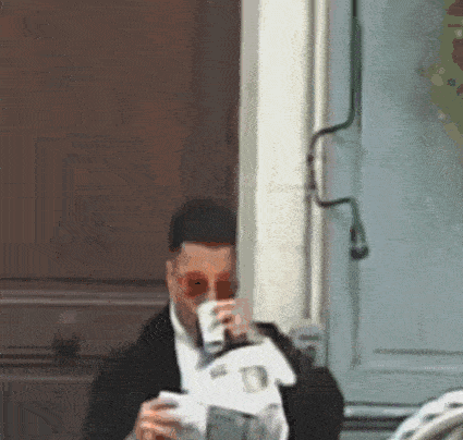 a man drinking a cup of coffee and reading a newspaper
