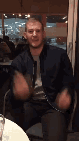 a man in a blue jacket is sitting at a table