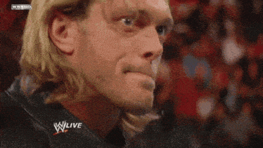 a man covering his face while watching a wrestling match on wwe live