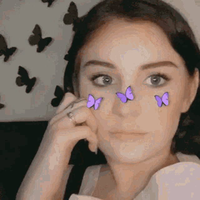 a woman with purple butterflies on her face is taking a selfie .