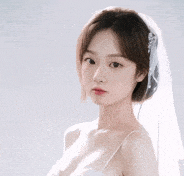 a woman in a white dress and veil is looking at the camera