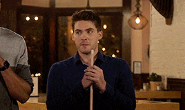 a man in a blue shirt holds a pool cue in his hands
