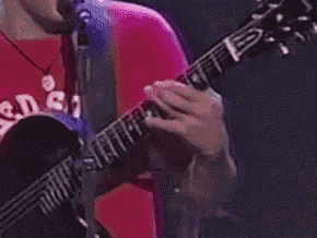 a man in a red shirt is playing a guitar in front of a microphone .