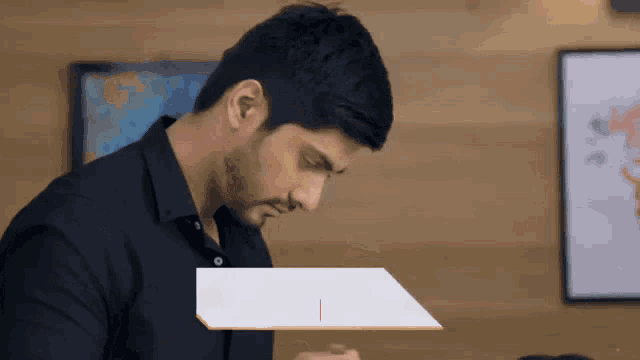 a man in a black shirt is looking down at a piece of paper