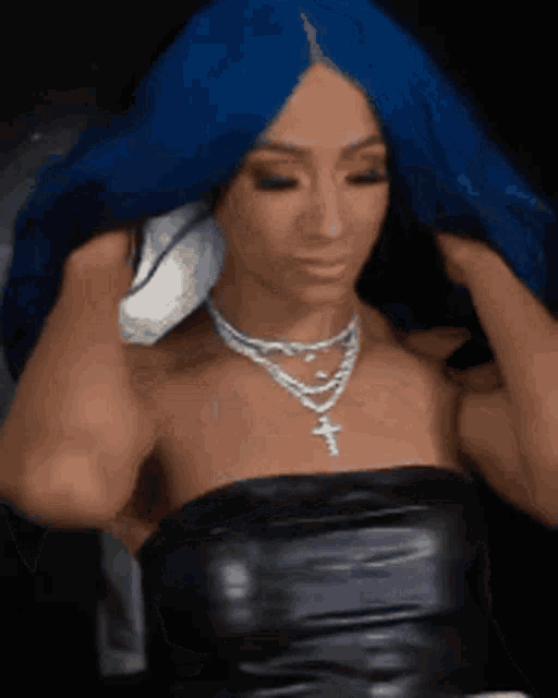 a woman with blue hair is wearing a black dress and a necklace with a cross .