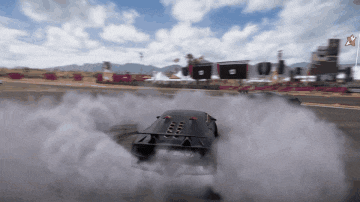 a black car is drifting on a track with smoke coming out of the tires