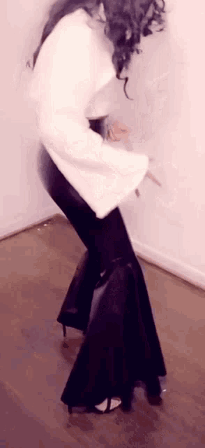 a woman in a white top and black pants is dancing .