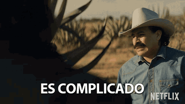 a man wearing a cowboy hat and a denim shirt says es complicado netflix