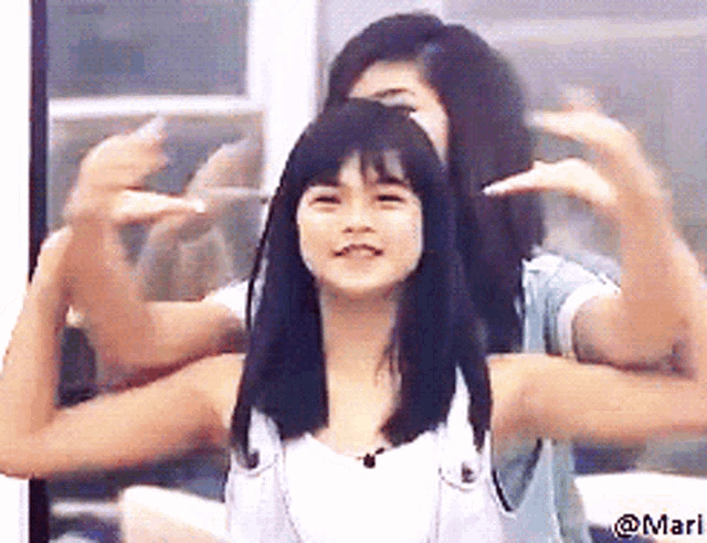 a picture of two girls with their arms outstretched has the name mari on the bottom right