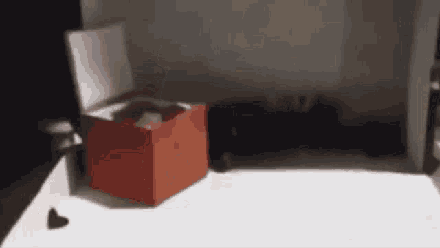 a red box is sitting on a white table in a dark room