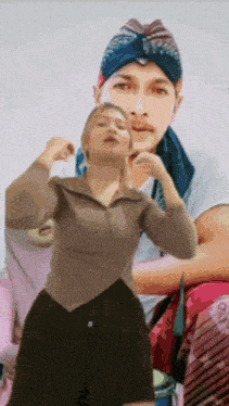 a woman is standing in front of a man wearing a bandana