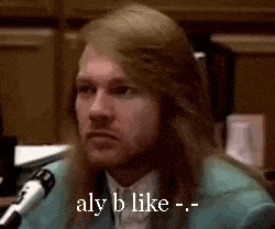 a man with long hair is talking into a microphone .