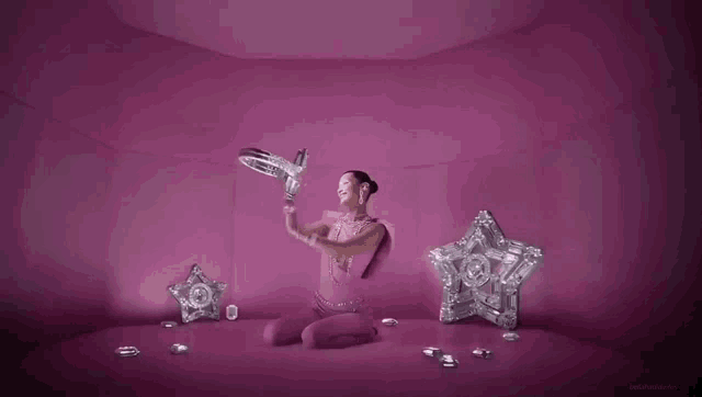 a woman in a pink outfit is sitting in a pink room surrounded by diamonds