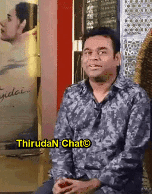 a man sitting in front of a sign that says ' thiruda chat ' on it
