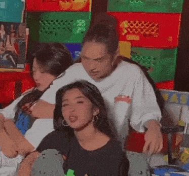 a group of young women are sitting next to each other in front of a stack of crates .