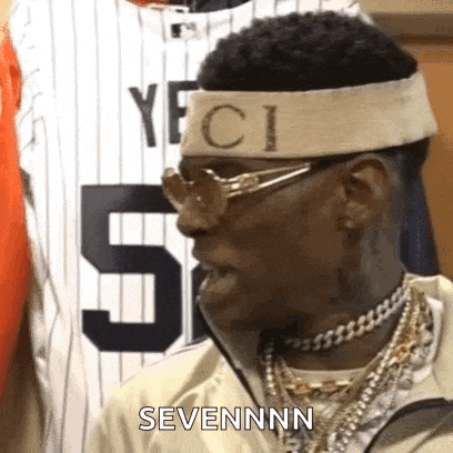 a man wearing a headband and sunglasses is standing in front of a baseball jersey and talking .