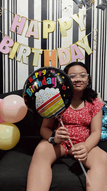 a girl is holding a balloon that says happy birthday
