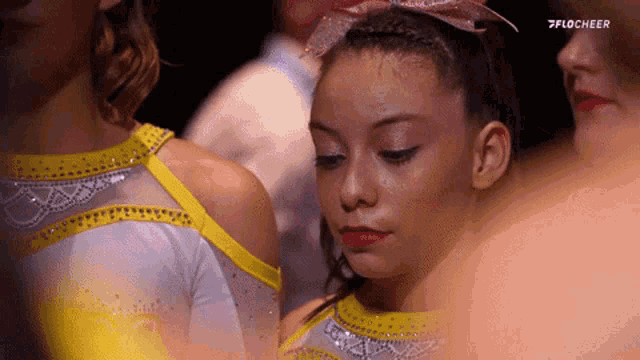 a cheerleader with a pink bow on her head is looking down