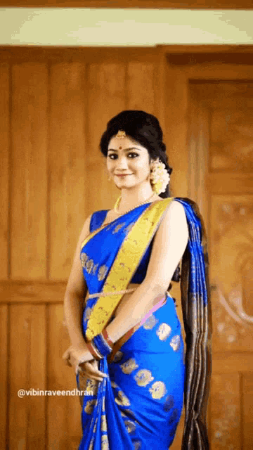 a woman wearing a blue saree with a yellow sash