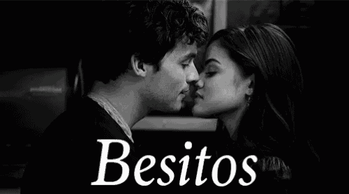 a black and white photo of a man and a woman kissing with the words besitos written above them