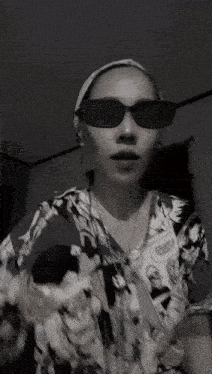 a black and white photo of a woman wearing sunglasses .