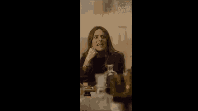 a woman is sitting at a table with bottles of wine and a sign that says planeta dodo