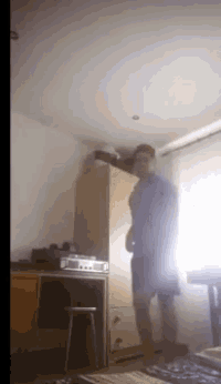 a man in a blue shirt is standing in a room with a window