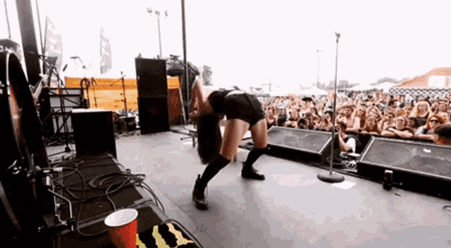 a woman is dancing on a stage in front of a crowd with a red cup in the foreground