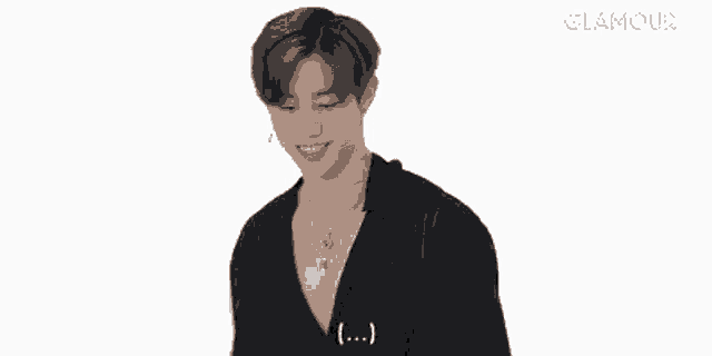a young man wearing a black shirt and a necklace is smiling on a white background .