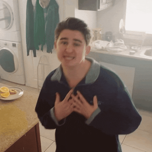 a young man in a kitchen with a plate of food and a washer and dryer behind him