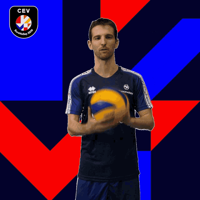 a man in a blue herbalife nutrition shirt holds a volleyball on his finger