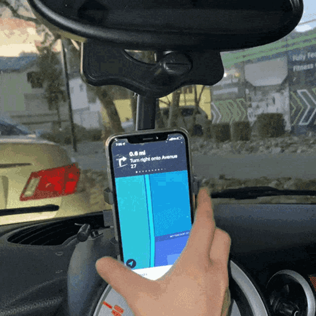 a person is holding a cell phone in front of a rear view mirror