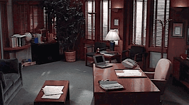 a living room with a desk and chairs and a laptop