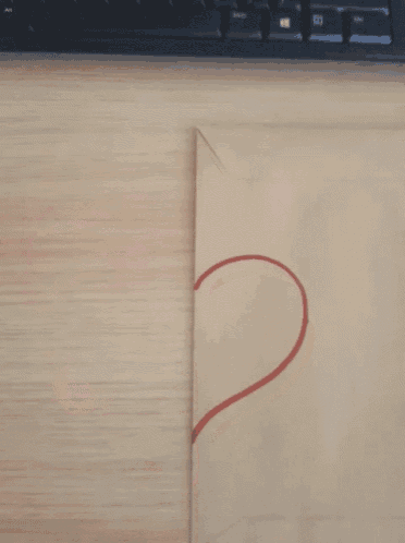 a hand draws a heart on an envelope with a keyboard in the background