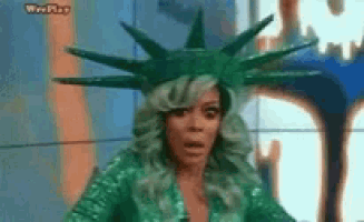 a woman is wearing a statue of liberty costume and looking surprised .