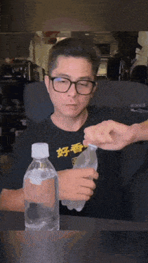 a man wearing glasses is holding a bottle of water with chinese writing on it