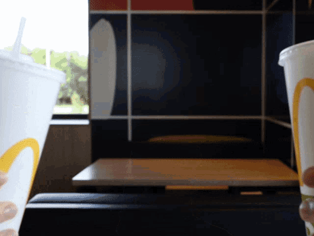 two mcdonald 's cups with straws in front of a table