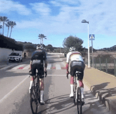 two cyclists are riding down a road with a sign that says " atencion "