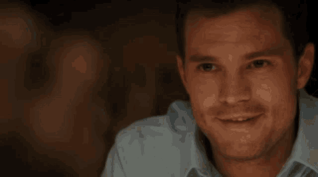 a close up of a man 's face in a dark room smiling at the camera .