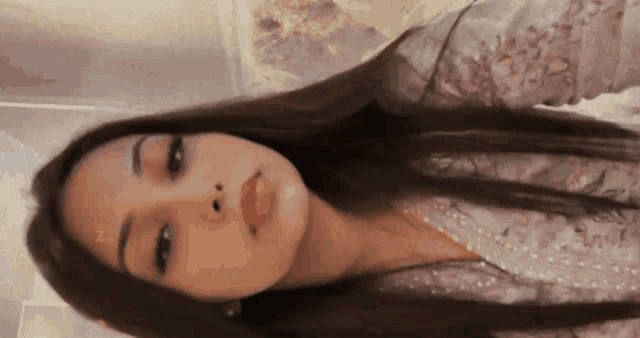 a close up of a woman 's face with long hair and a pink shirt .